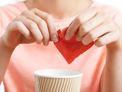A woman adds artificial sweetener to a drink. The paranoia over the health dangers of aspartame can be traced back to an early Internet hoax.