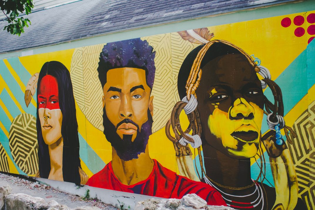 A painting of (left to right) a Lucayan person, a modern Bahamian and an African tribesman, by artist Darchell Henderson