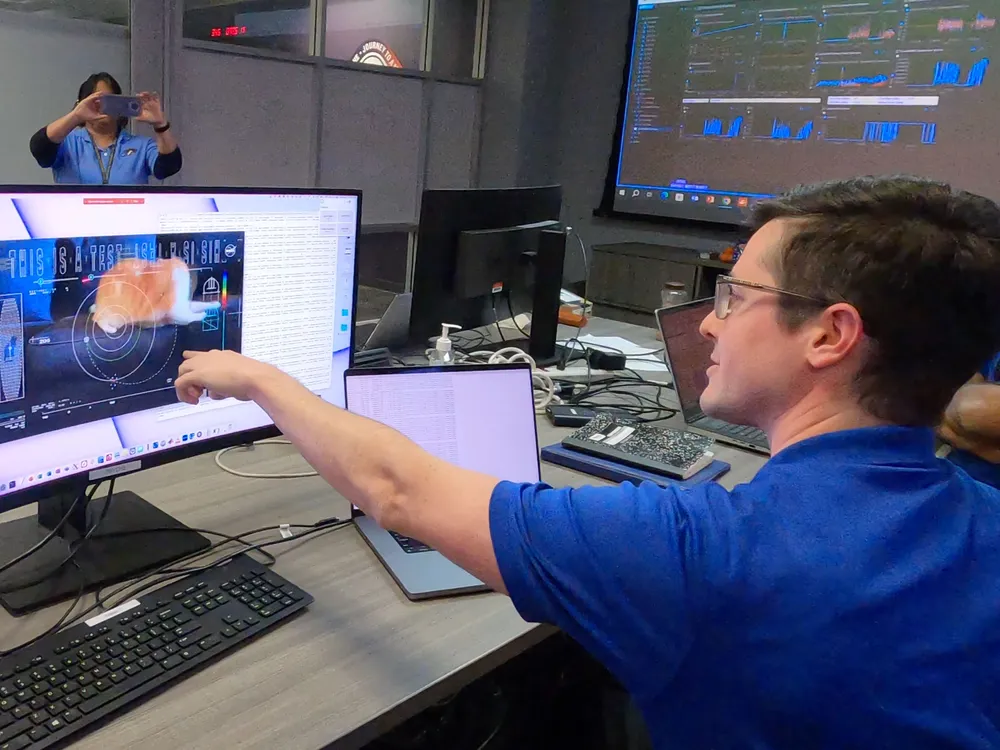 man points to a computer screen with a cat on it