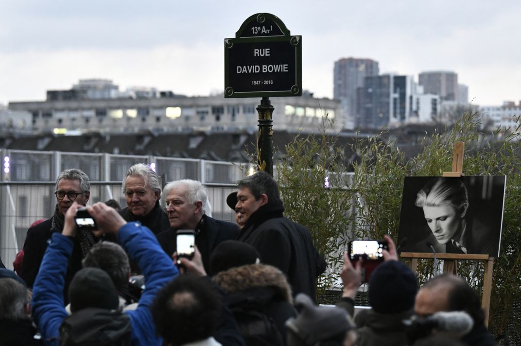 Fans gather in front of sign that says Rue David Bowie