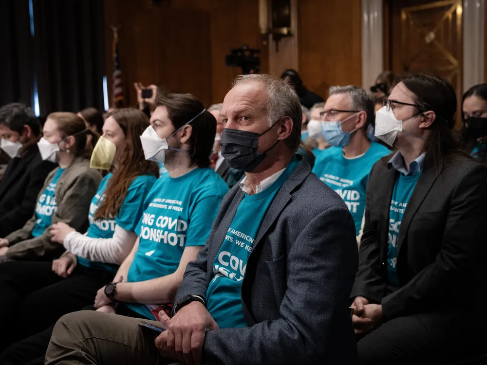 People with masks and blue t-shirts sitting in rows