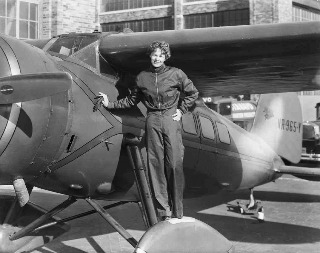 Woman in a jumpsuit standing next to plane