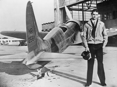 Howard Hughes stands with his first plane, the H-1.