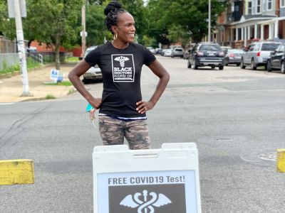 Surgeon Ala Stanford takes a pause from testing while standing near one of her group's signs in North Philadelphia.