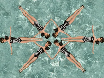 six Barbie dolls wearing zebra striped swimsuits in a synchronized formation in a swimming pool